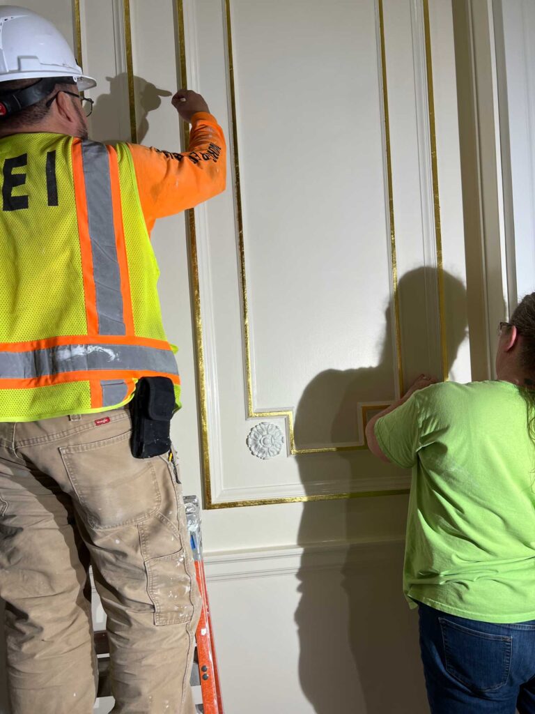 Amy and Oscar are applying the gold leaf to the woodwork on the first floor.
